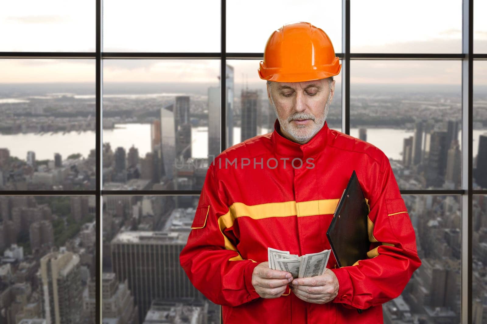 Portrait of construction worker in red uniform is counting money. by super_picture