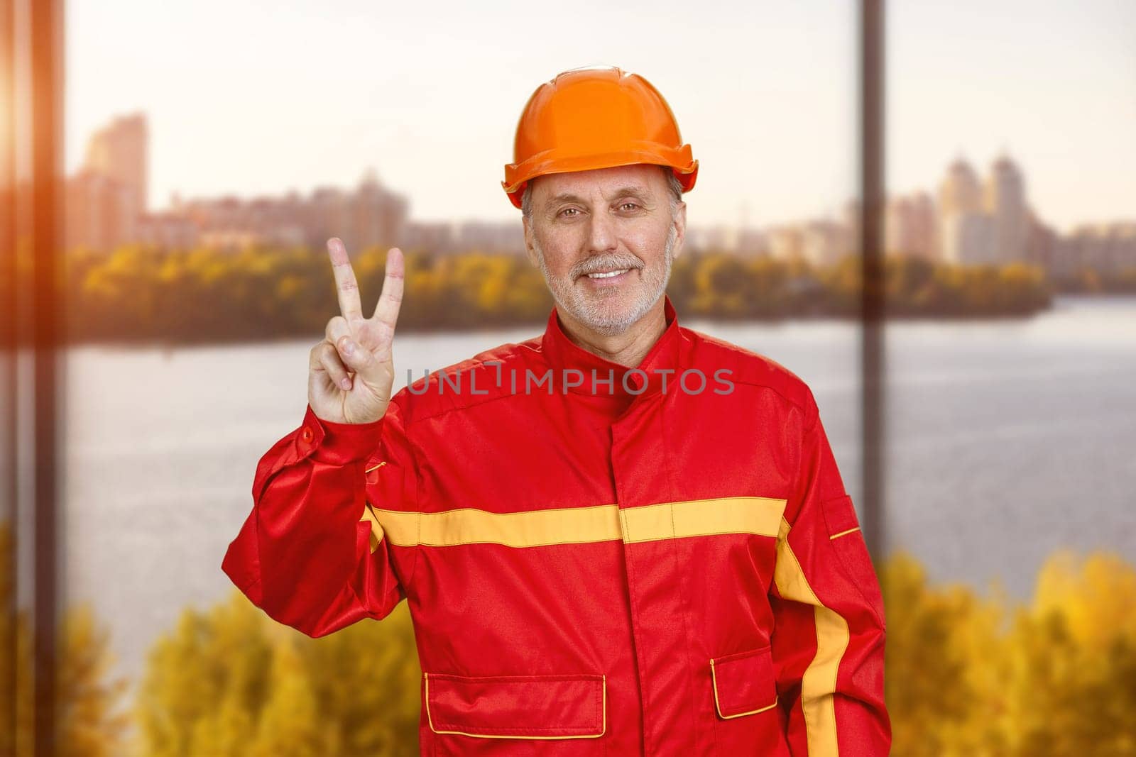 Happy smiling construction worker shows victory gesture sign. by super_picture