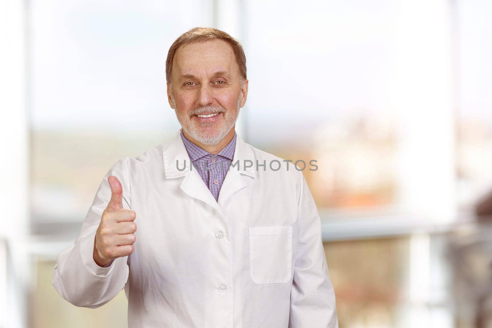 Happy male senior medic in white coat shows thumb up. by super_picture