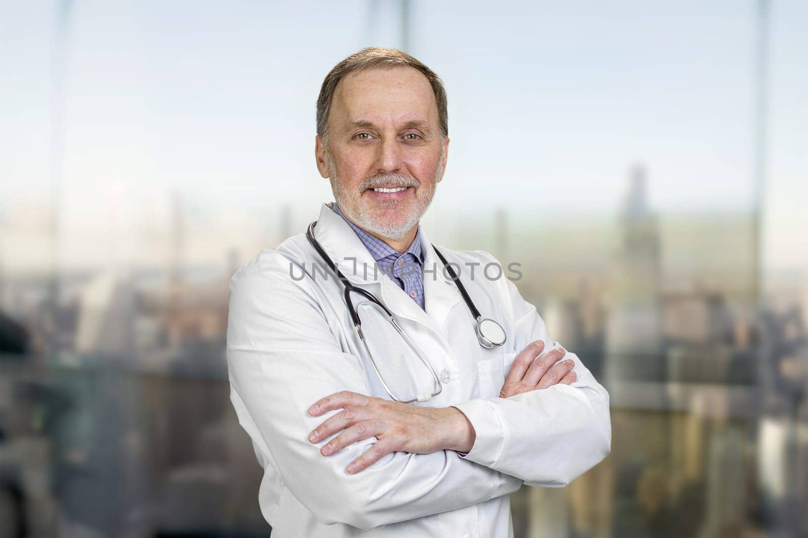 Portrait of smiling senior doctor with folded arms. by super_picture