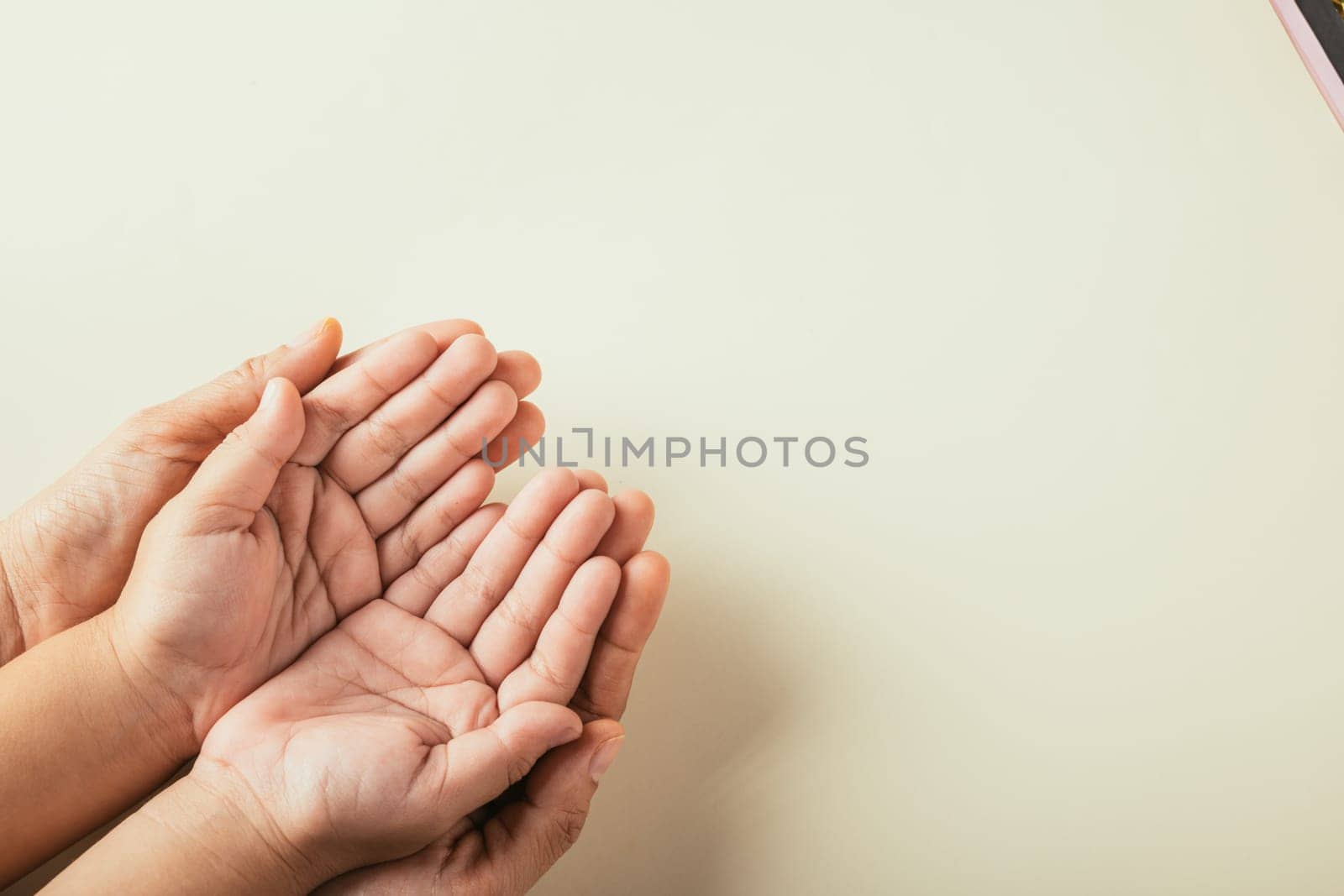 Parents and kid holding empty hands top view isolated on color background. Commemorating Family Day embodying togetherness and generational support. by Sorapop