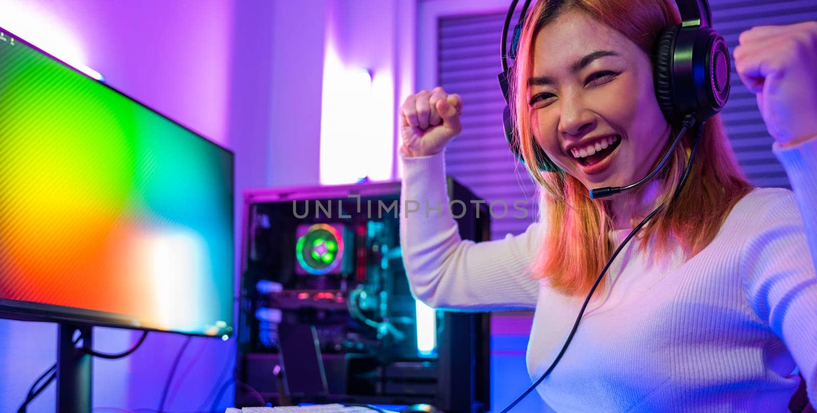 Happy Gamer young plays online video games computer she raises hands to wins tournament by Sorapop