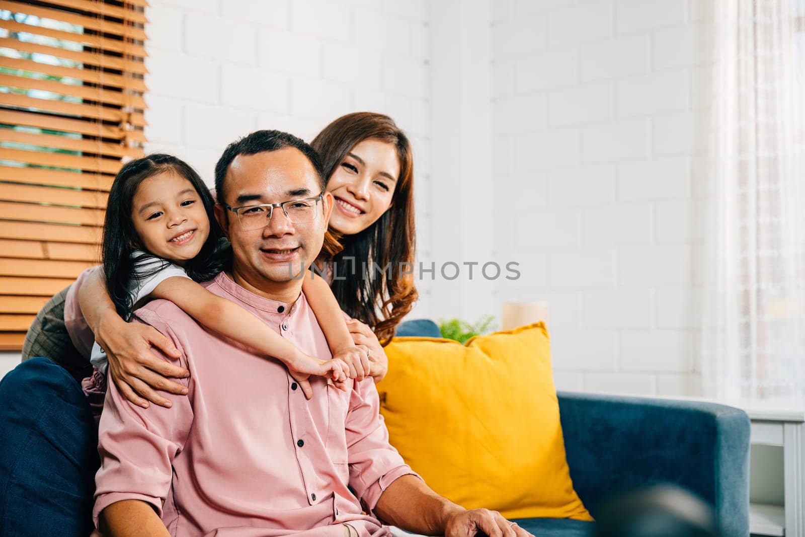 A modern home becomes the backdrop for a joyful family moment on the sofa. Parents daughters and siblings embrace bond and laugh radiating happiness and togetherness.