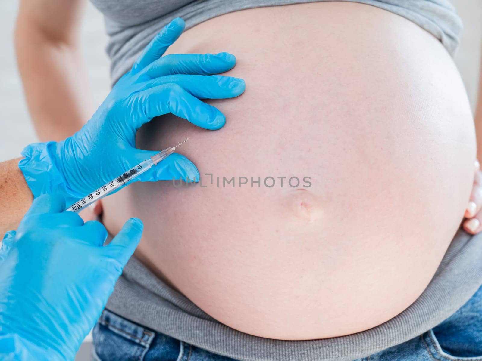 Doctor gives an injection in the stomach of a pregnant woman. by mrwed54