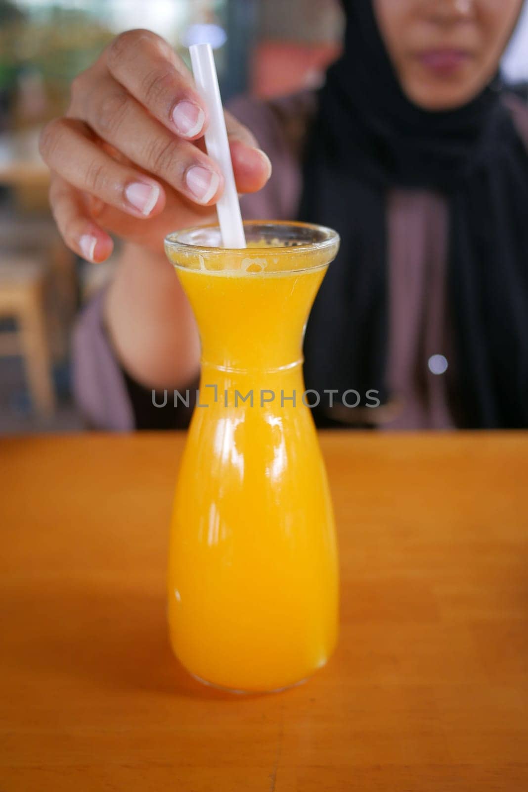 women hand holding a glass of orange juice by towfiq007