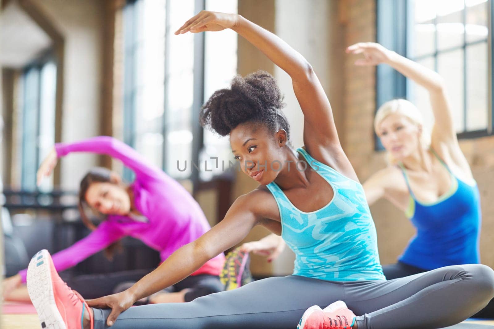 Black woman, instructor and yoga class at gym, stretch and yogi trainer for exercise on mat. Female person, floor and confident for pilates or spiritual fitness, flexibility and health in performance.