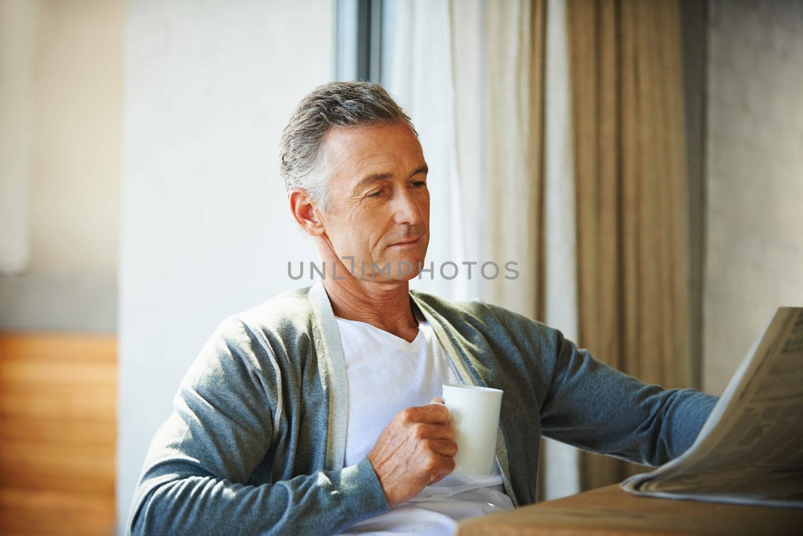 Mature, man and newspaper for reading in home, relax and information or articles in morning with coffee. News, breakfast table and rest and calm for entertainment pages, current events in apartment.
