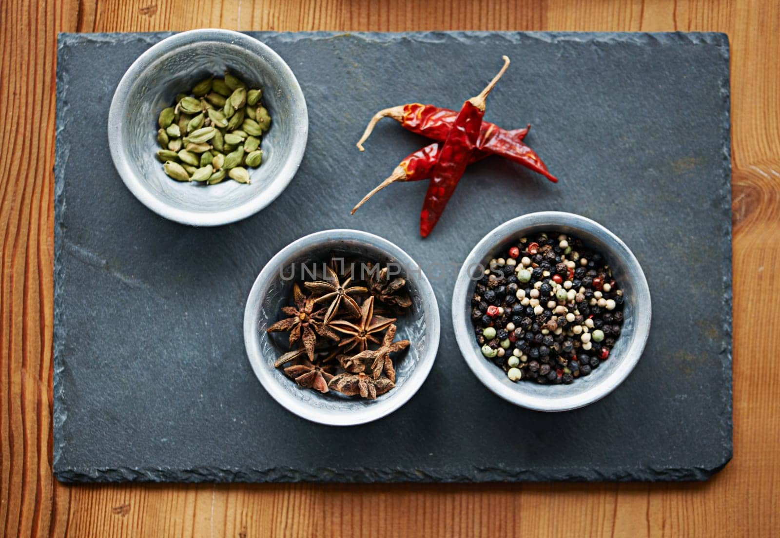 Chilli, ingredients and spices in bowl above on board for cooking for cuisine, meal and lunch. Condiments, seasoning and dried pepper for gourmet dinner with cardamon seeds, star anise and peppercorn.