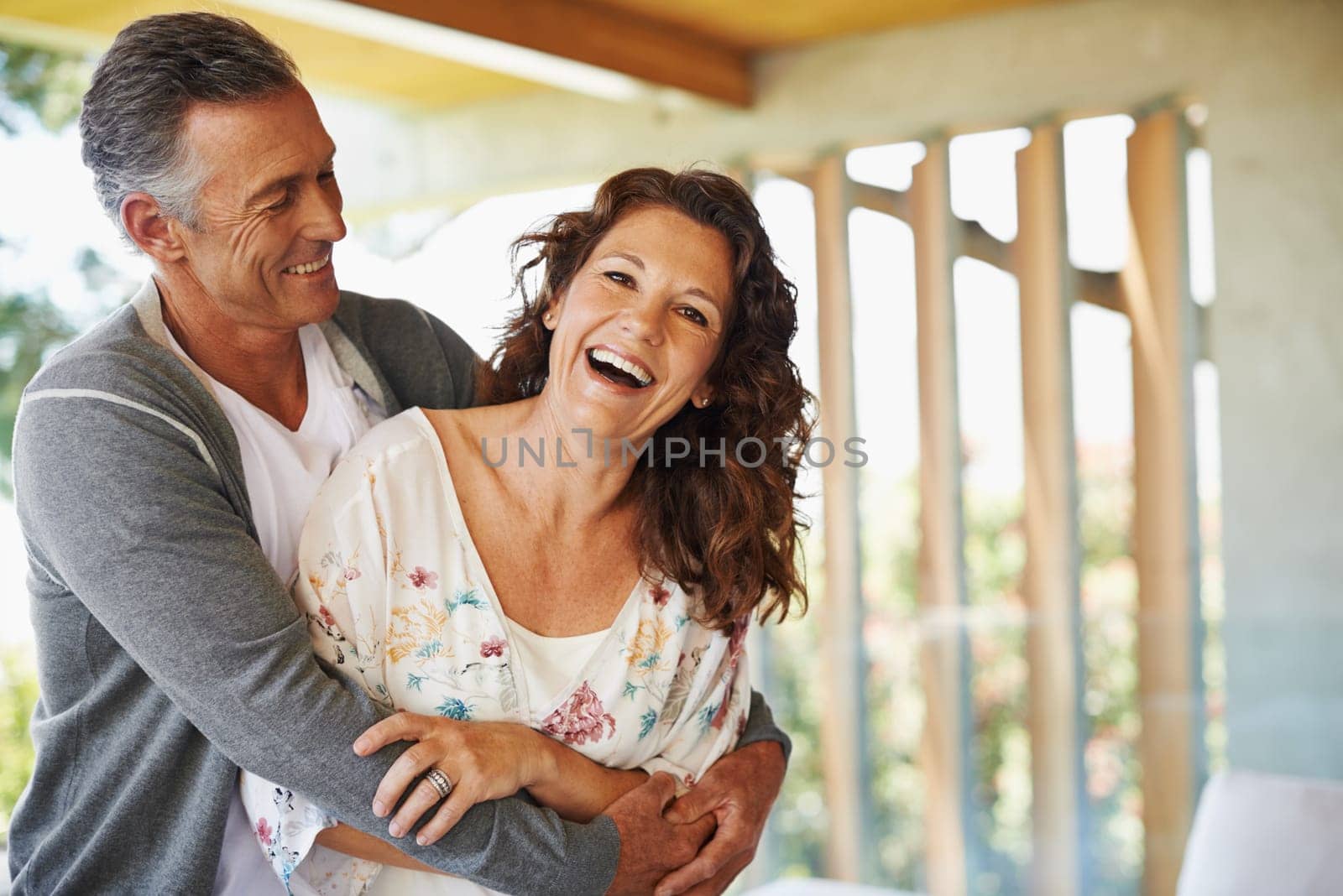 Laughing, portrait or mature couple hug in home for support, wellness or love for care, marriage or trust. Smile, fun or happy woman bonding with man in retirement, break or house to relax together.