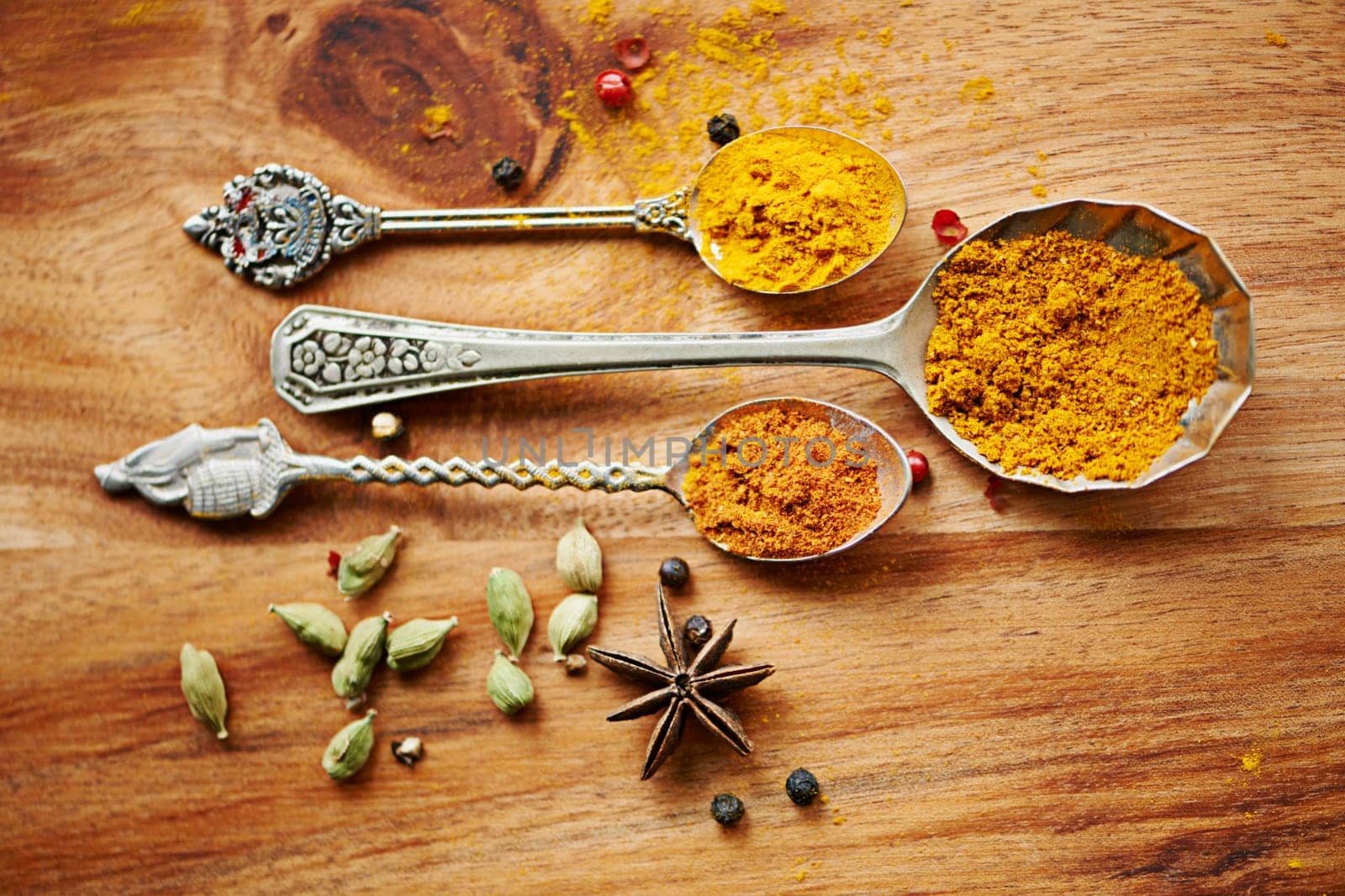 Spoons, spice and selection of seasoning for gourmet on kitchen table, turmeric and cardamom for meal. Top view, cooking and options for spicy diet in Indian culture, art and food preparation by YuriArcurs