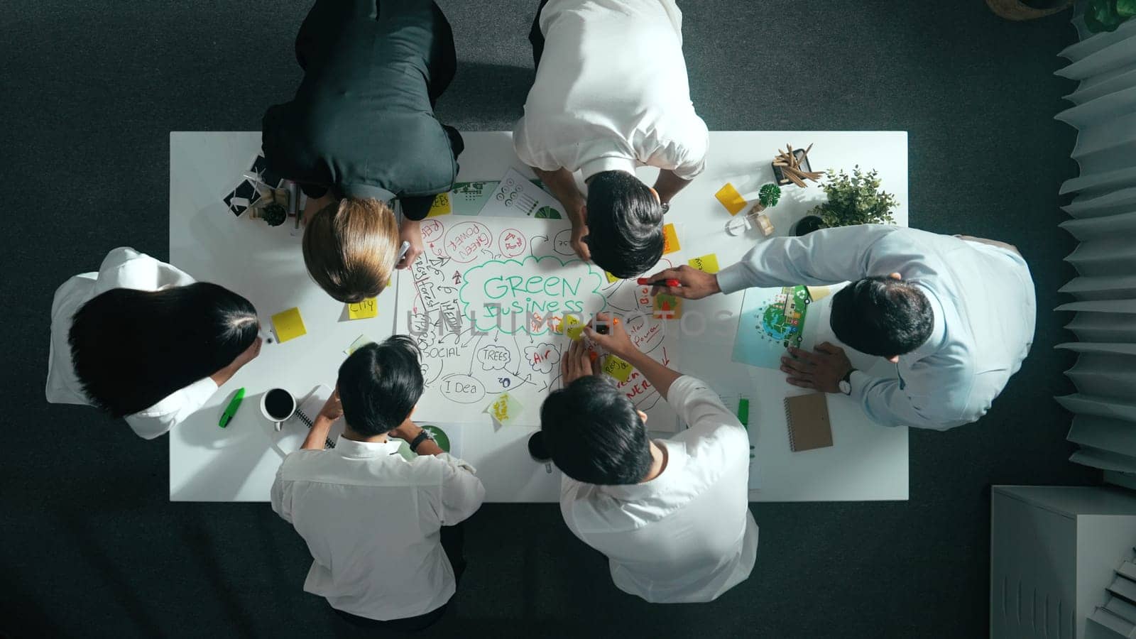 Top down view of business team discussing about using clean energy and sustainable investment at meeting table with wind mill, document with environmental graph and wooden house model. Alimentation.