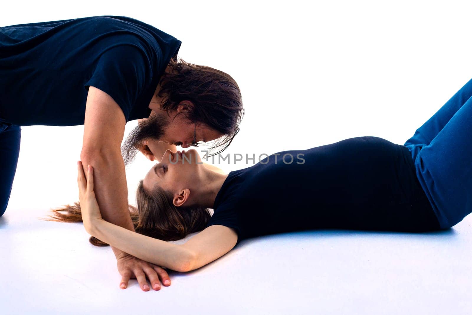 Beautiful pregnant woman and her handsome husband are kissing while spending time together isolated over white background wall. beautiful young couple expecting baby standing together and touching belly