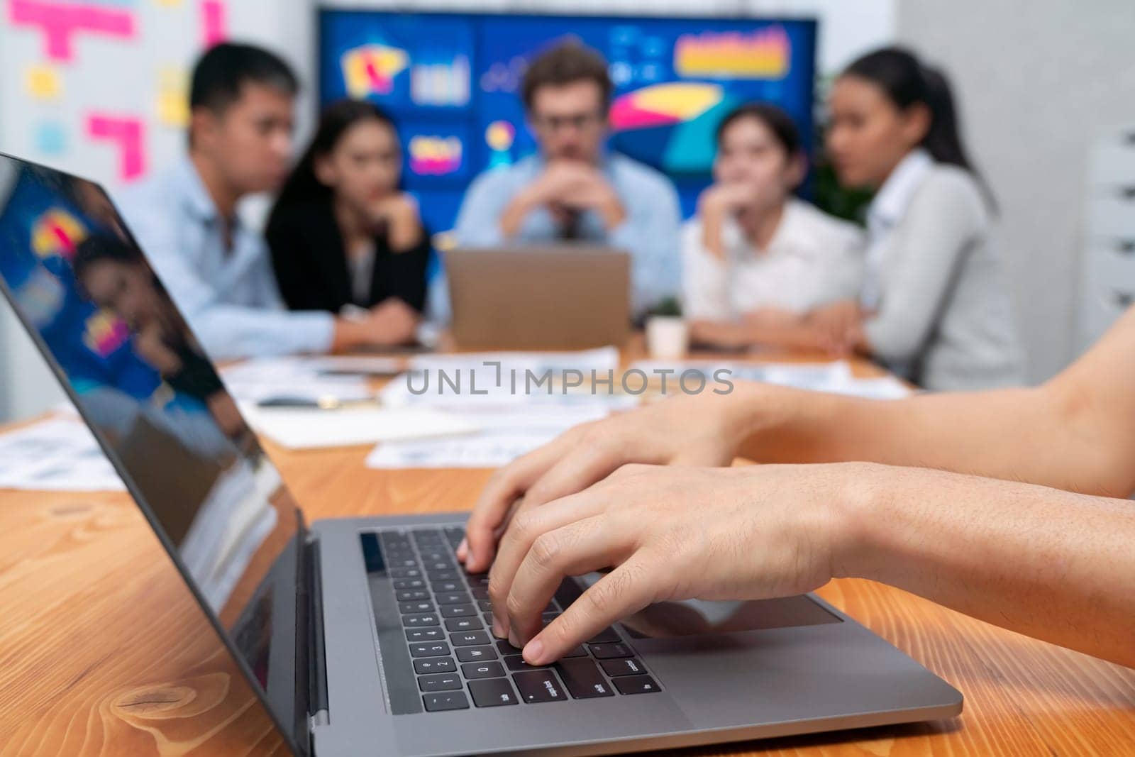 Closeup hand typing keyboard laptop with blurred background of business people using laptop to analyze financial data or data analysis display on screen background. Meticulous