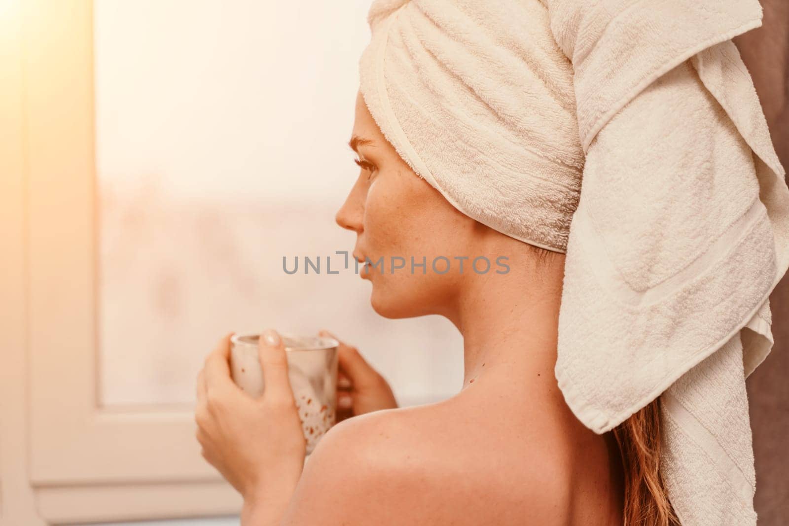 Young serene relaxed woman in spa bath towel drinking hot beverage tea coffee after taking shower bath at home. Beauty treatment, hydration concept