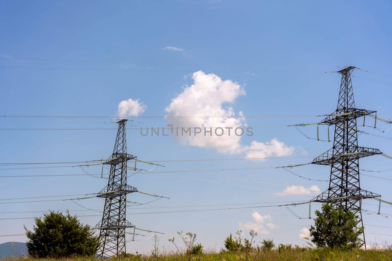 High voltage towers with sky background. Power line support with wires for electricity transmission. High voltage grid tower with wire cable at distribution station. Energy industry, energy saving.