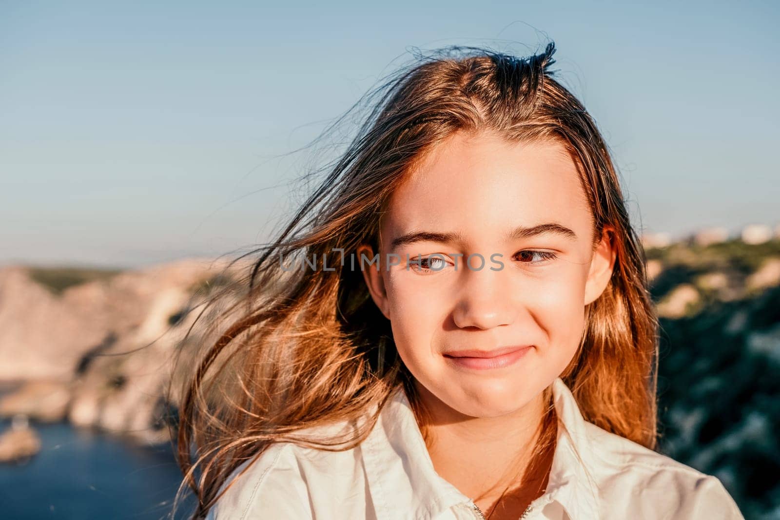 Adorable teenage girl outdoors enjoying sunset at beach on summer day. Close up portrait of smiling young romantic teenager girl with long hair on beach at summer evening. Travel and holidays by panophotograph