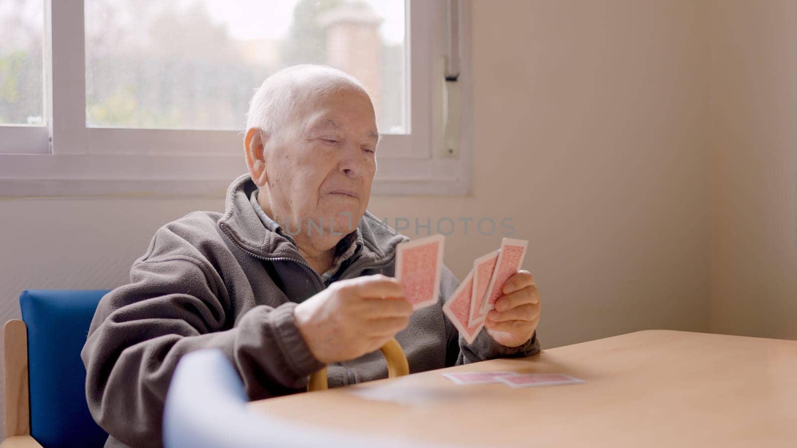 Senior man sorting his cards ready to play in a geriatric
