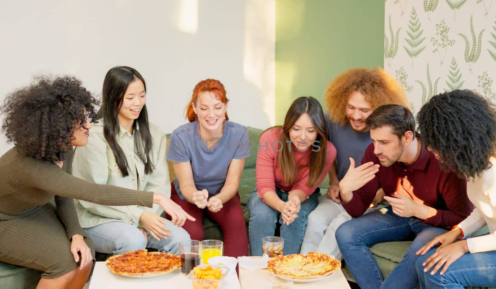 Multiracial group of happy friends eating pizza at home by ivanmoreno