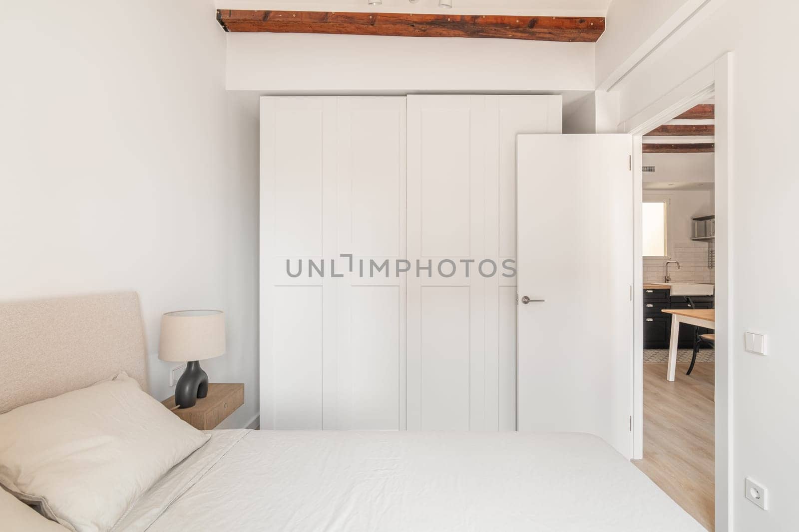 Closet and comfortable double bed in white bedroom by apavlin