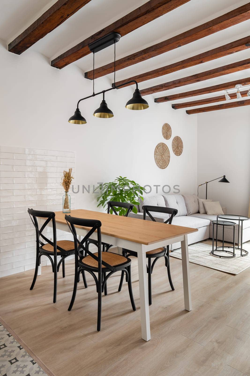 Dining table with chairs under metal luster in studio apartment. Cosy place to eat with vintage furniture in home interior. Elegant design