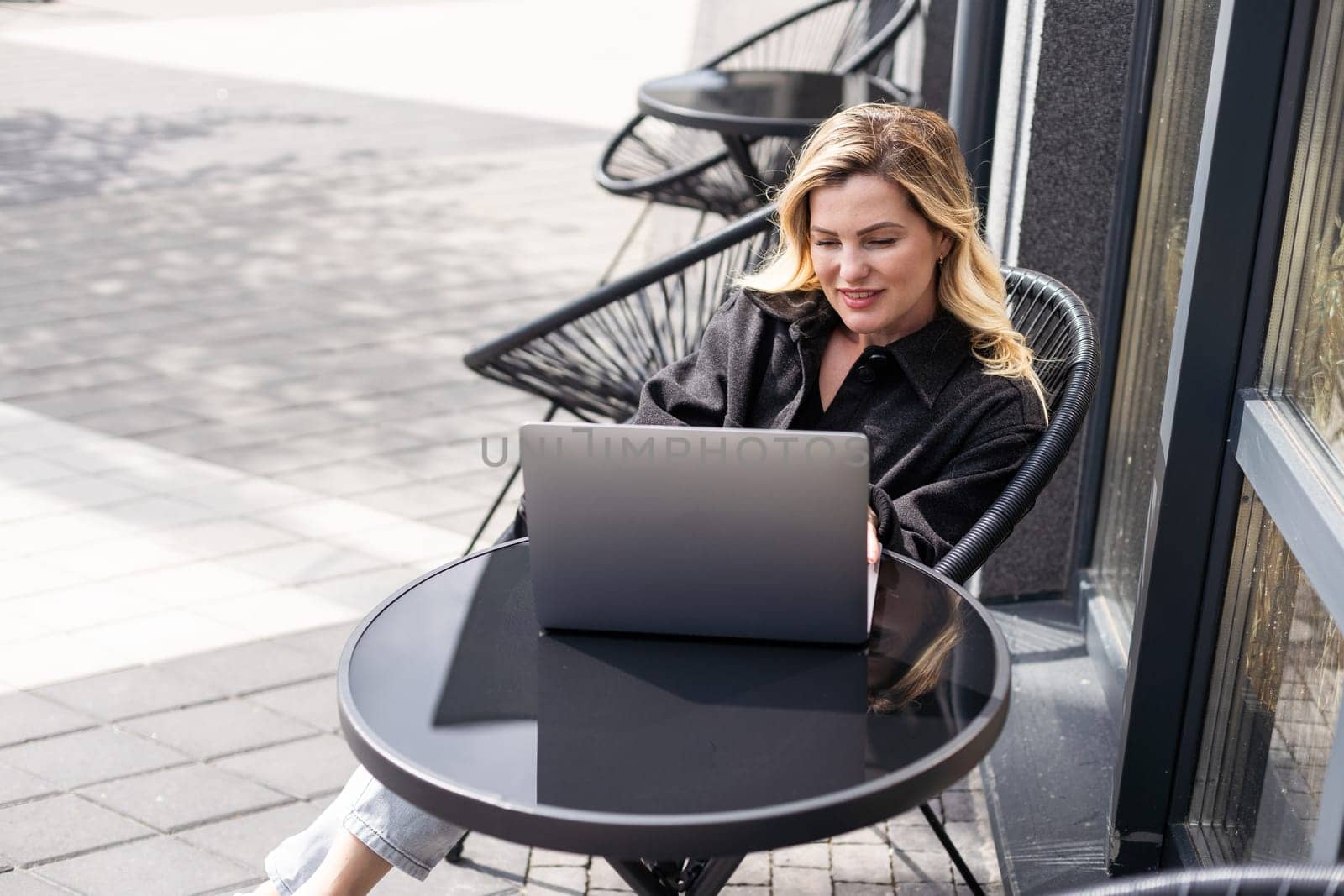 Businesswoman working with laptop in outdoor cafe. Corporate blog by Andelov13
