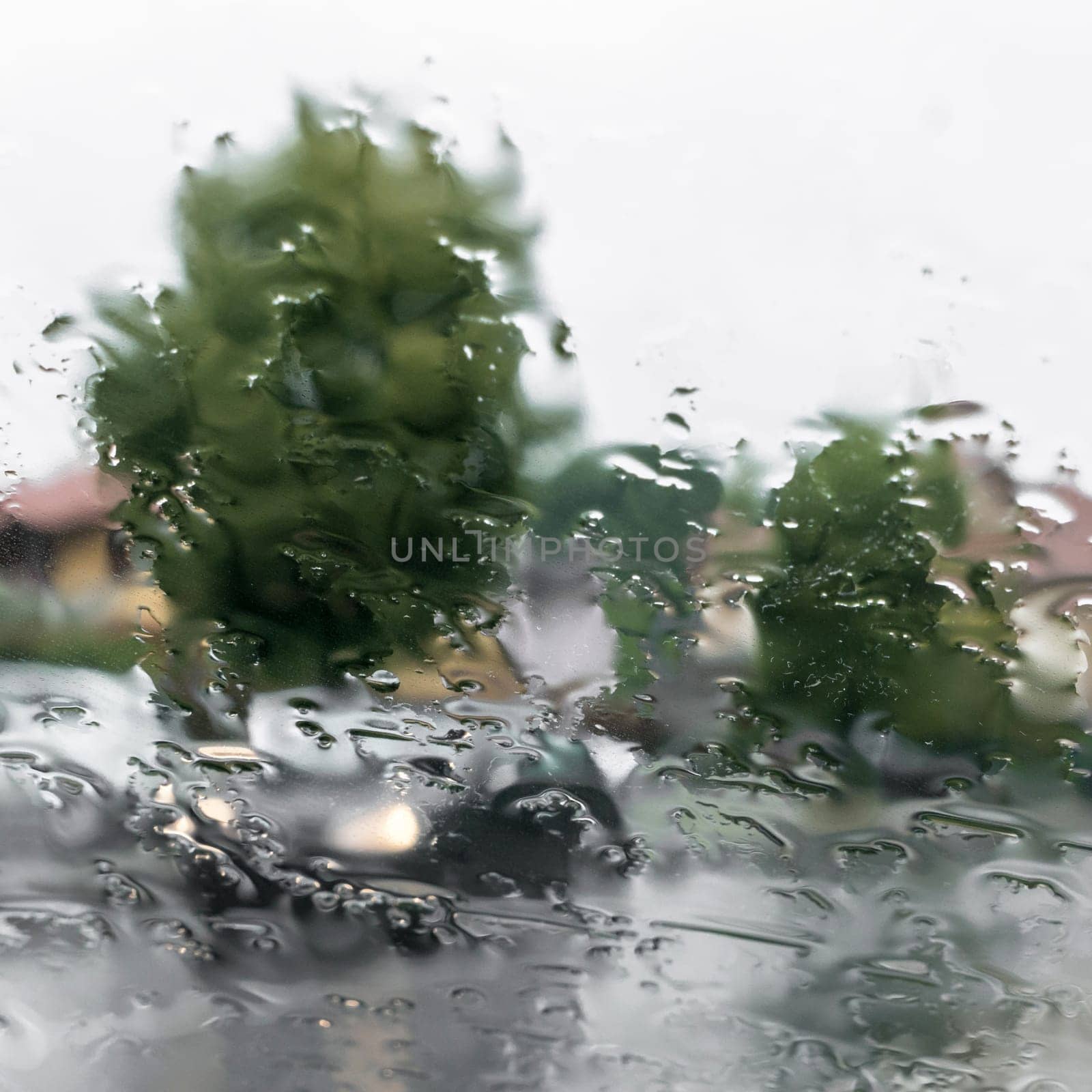 Blurred view of road through wet car window. Rainy weather. Safety.
