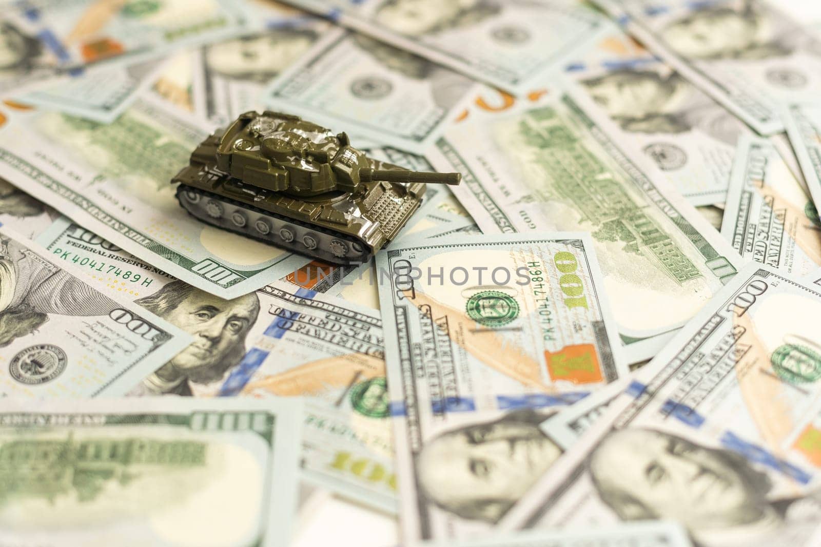 Toy tank on US hundred dollar bills banknotes close up. The concept of war costs, military spending and economic crisis. High quality photo