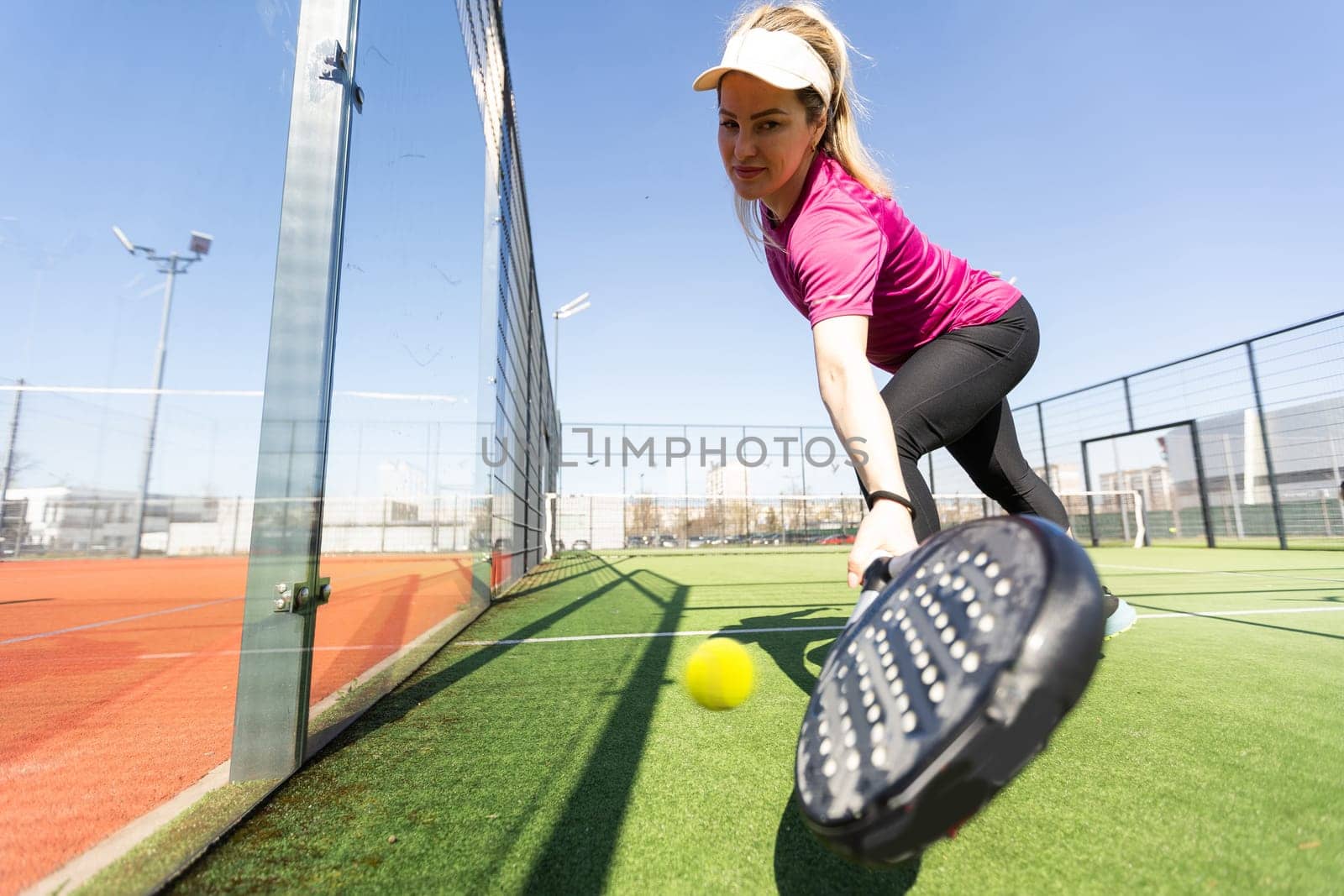 Young sporty woman playing padel game in court on sunny day by Andelov13