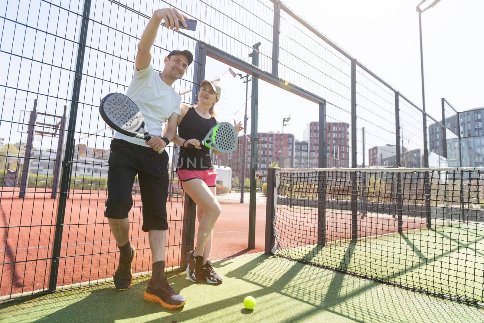 Sports couple with padel rackets posing on tennis court by Andelov13