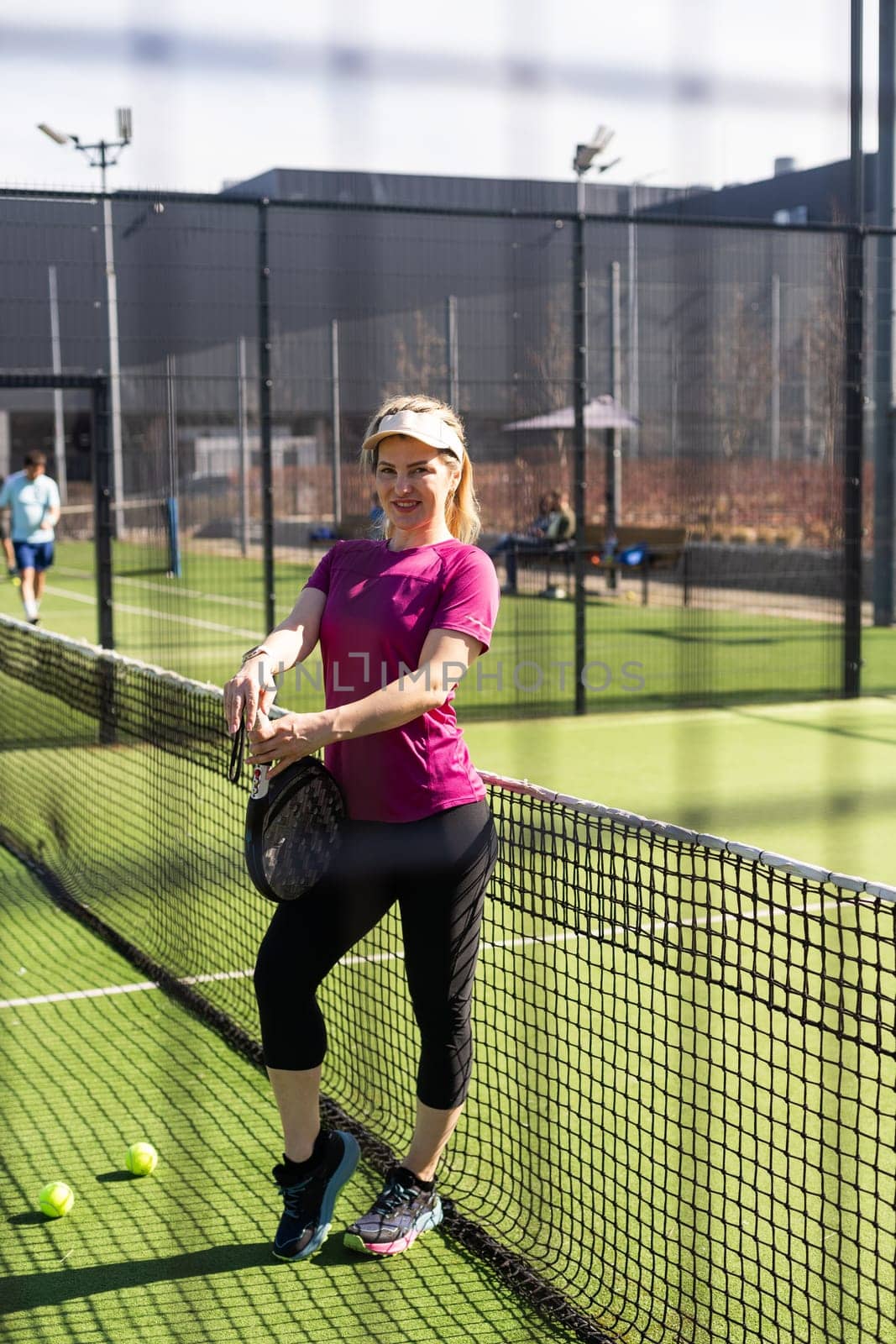 Happy female paddle tennis player during practice on outdoor court looking at camera. Copy space. High quality photo