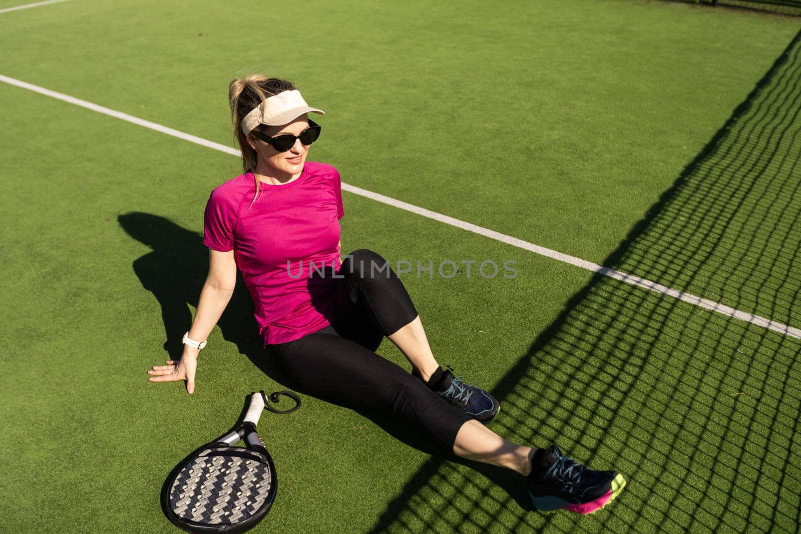 Young sporty woman playing padel game in court on sunny day by Andelov13