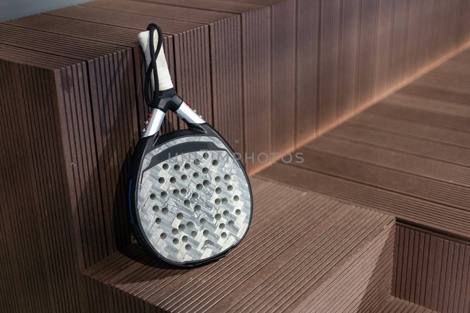Closeup view of a paddle racket in a padel tennis court near the net. Sport, health, youth and leisure concept. Sporty equipment. White lines in background. High quality photo