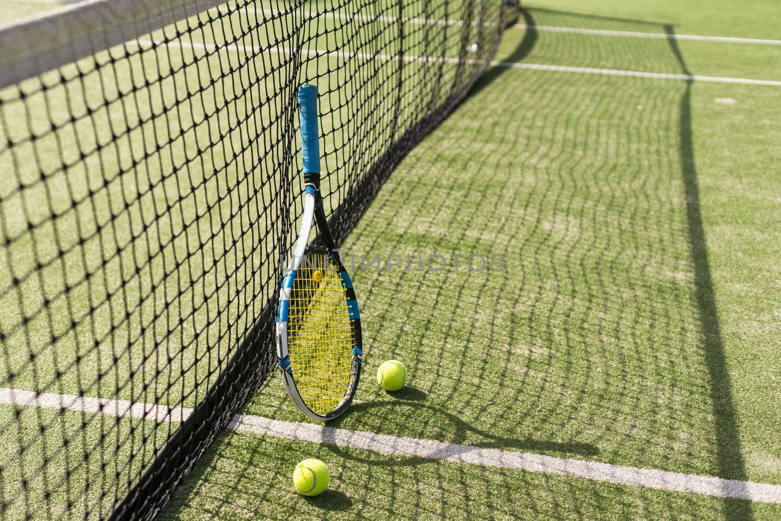 Tennis racquet and tennis balls at the net on the lines on a tennis court. . High quality photo