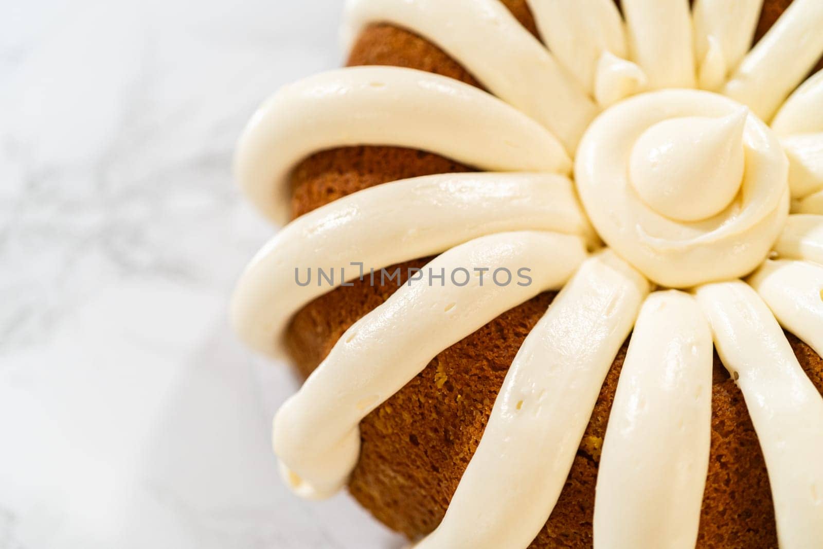 Icing the pumpkin bundt cake with cream cheese frosting and decorating it with chocolate leaves.