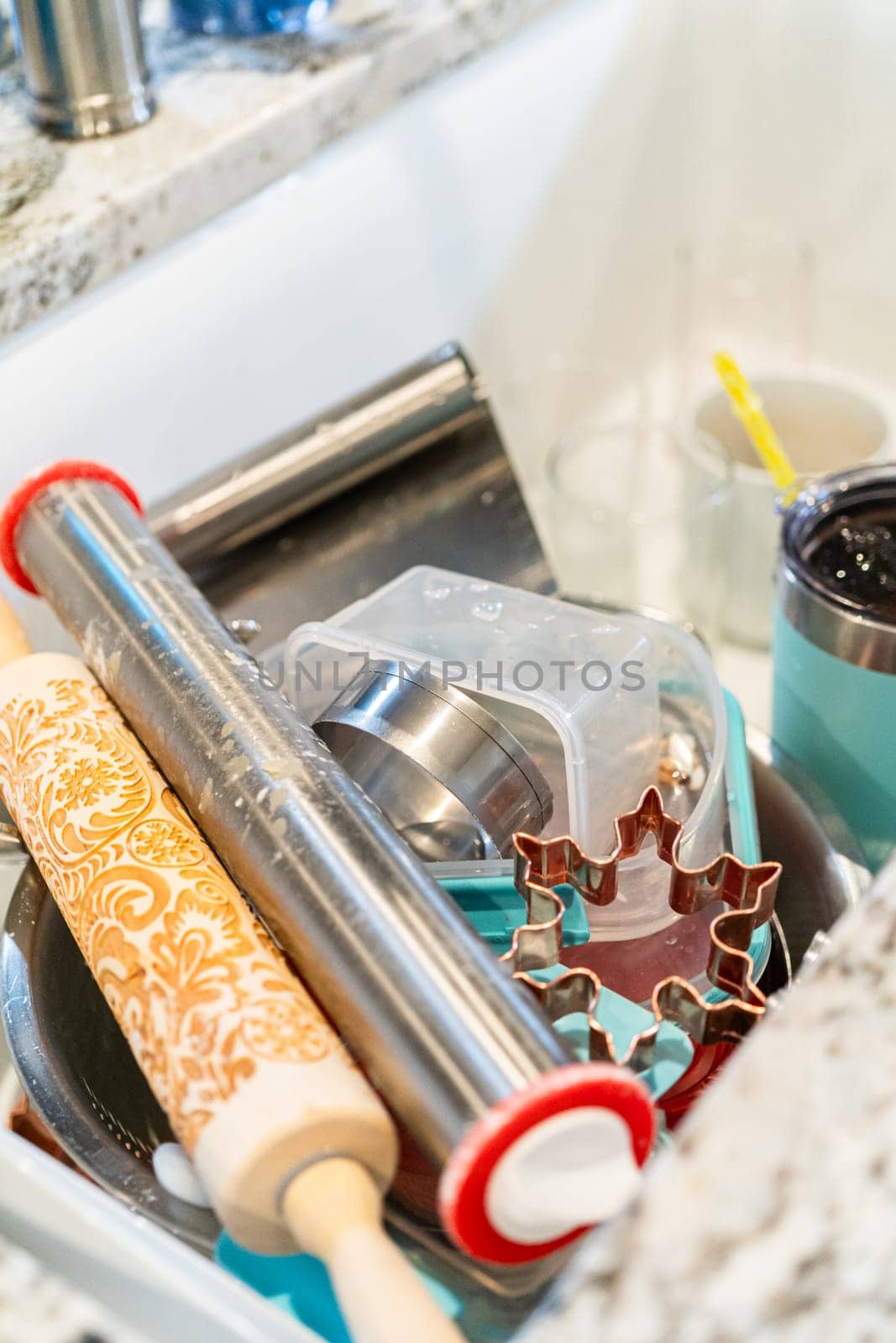 After a fun day of baking snowflake sugar cookies, the kitchen sink is filled with a pile of dirty dishes waiting to be cleaned.