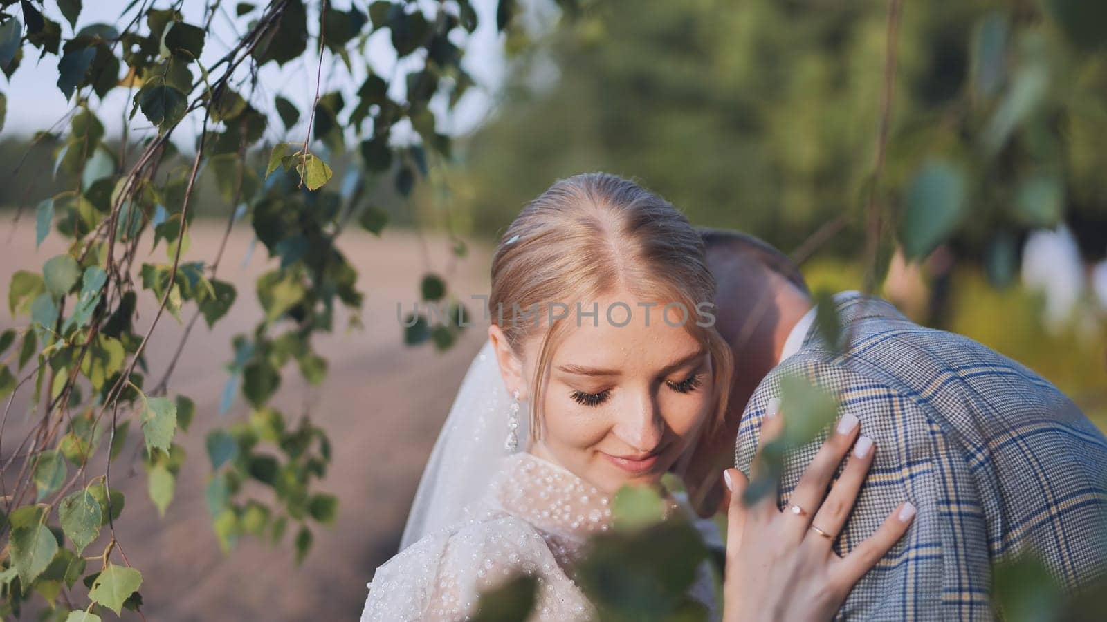 Bride and groom touching and enjoying each other against a backdrop of birch tree branches. by DovidPro