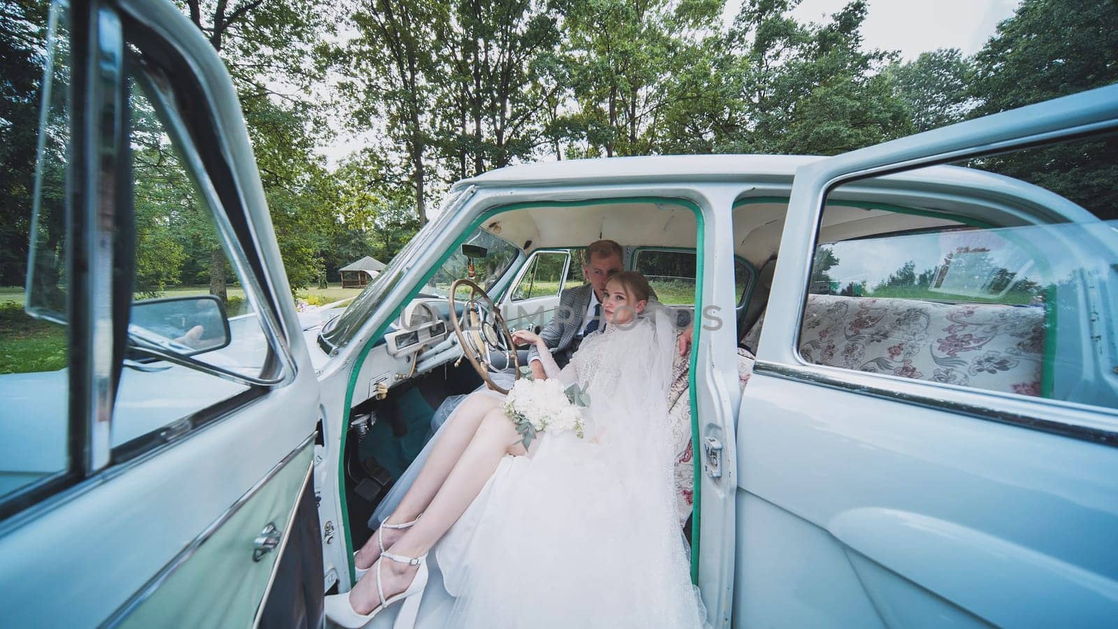 Bride and groom enjoying each other in a retro car. by DovidPro