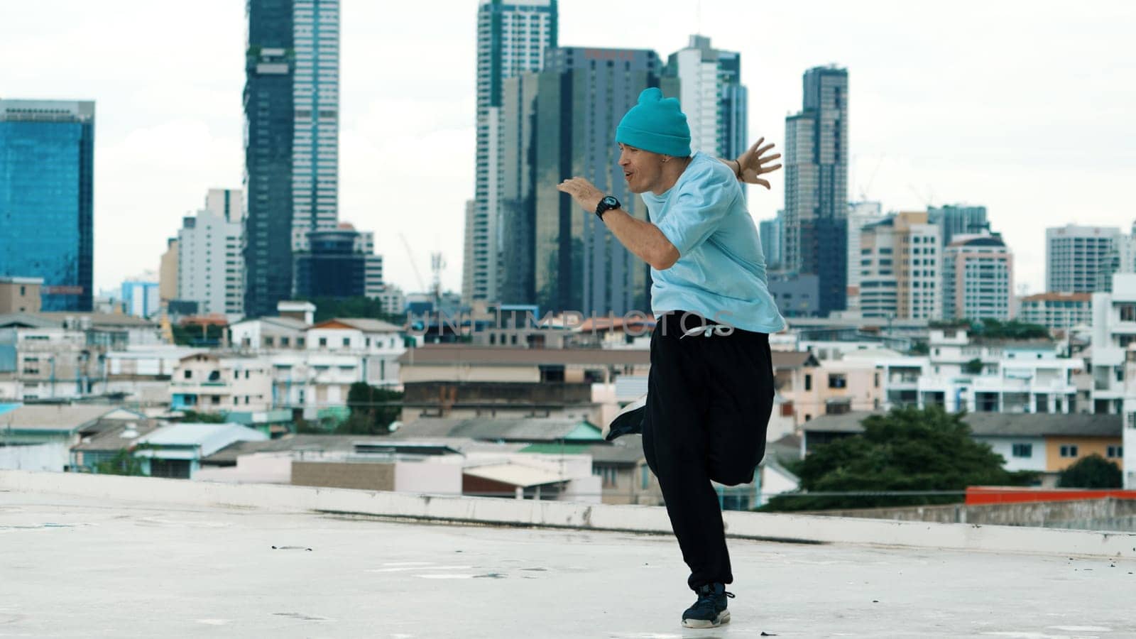 Skilled caucasian B-boy dancer practicing street dancing at rooftop. Endeavor. by biancoblue