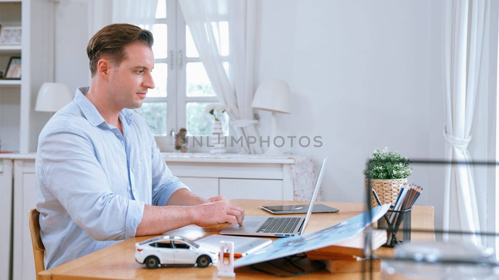 Car design engineer working on car prototype for automobile business at home office. Automotive engineering designer carefully analyze, finding flaws and improvement for car design. Synchronos