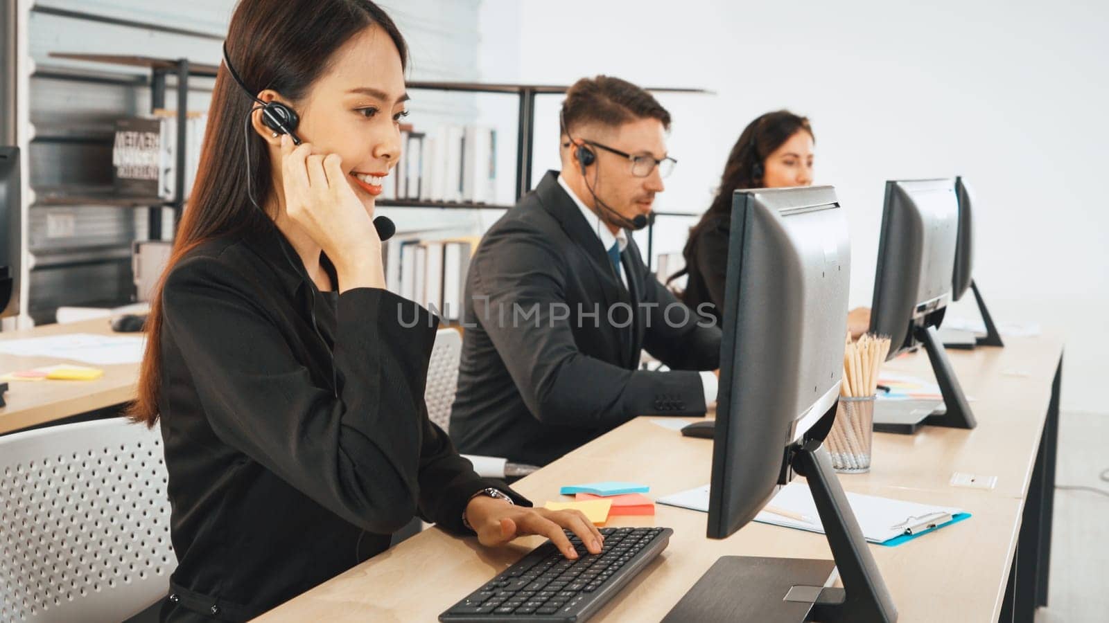 Business people wearing headset working in office to support remote customer or colleague. Call center, telemarketing, customer support agent provide service on telephone video conference call. Jivy