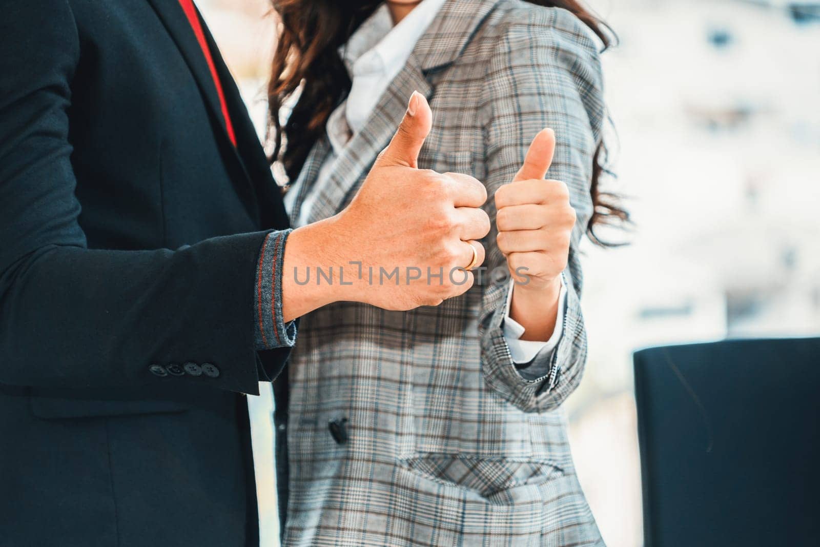 Two happy businesspeople holding thumbs up in modern office . Jivy