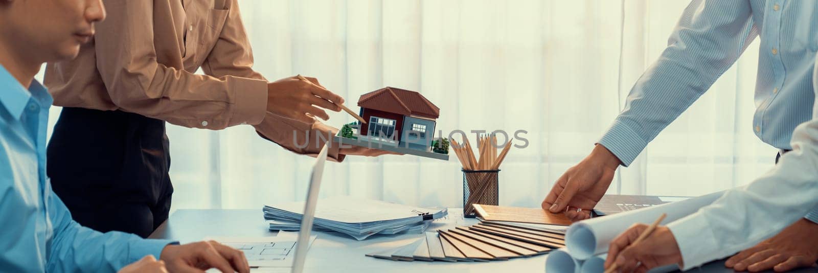 Group of interior designer team in meeting, discussing with engineer on interior design and planning for house project blueprint and model, choosing color sample and mood board materials. Insight