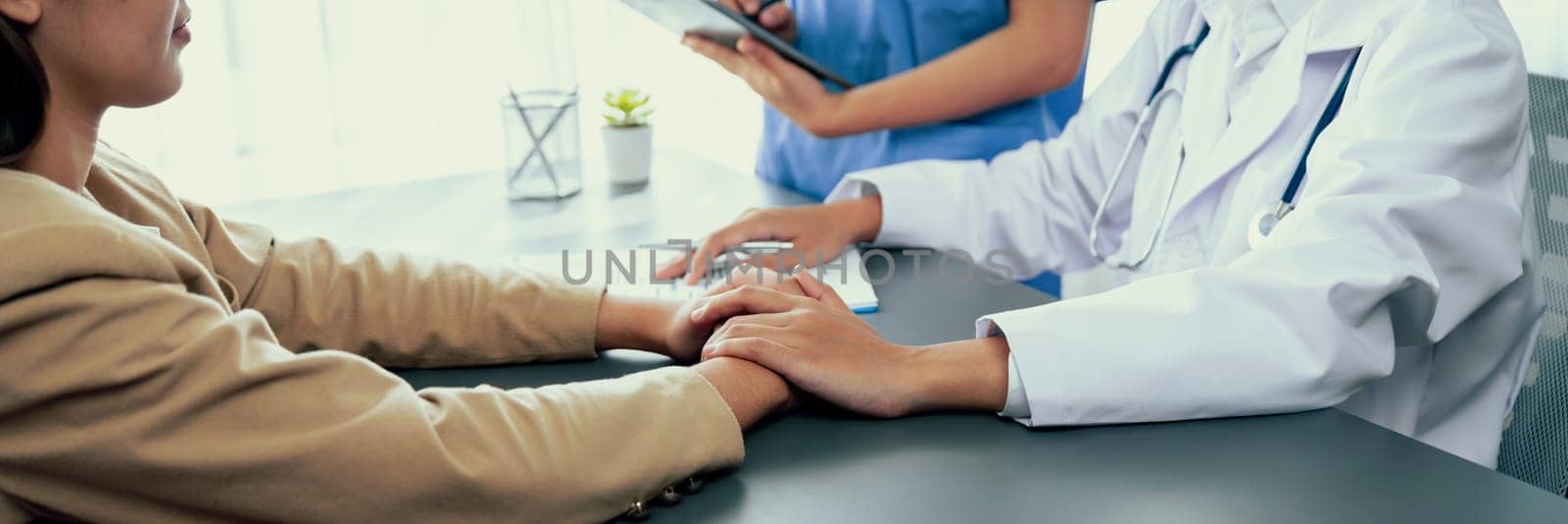 Doctor show medical diagnosis report and providing compassionate healthcare consultation while holding young patient hand for being supportive and professional in doctor clinic office. Neoteric