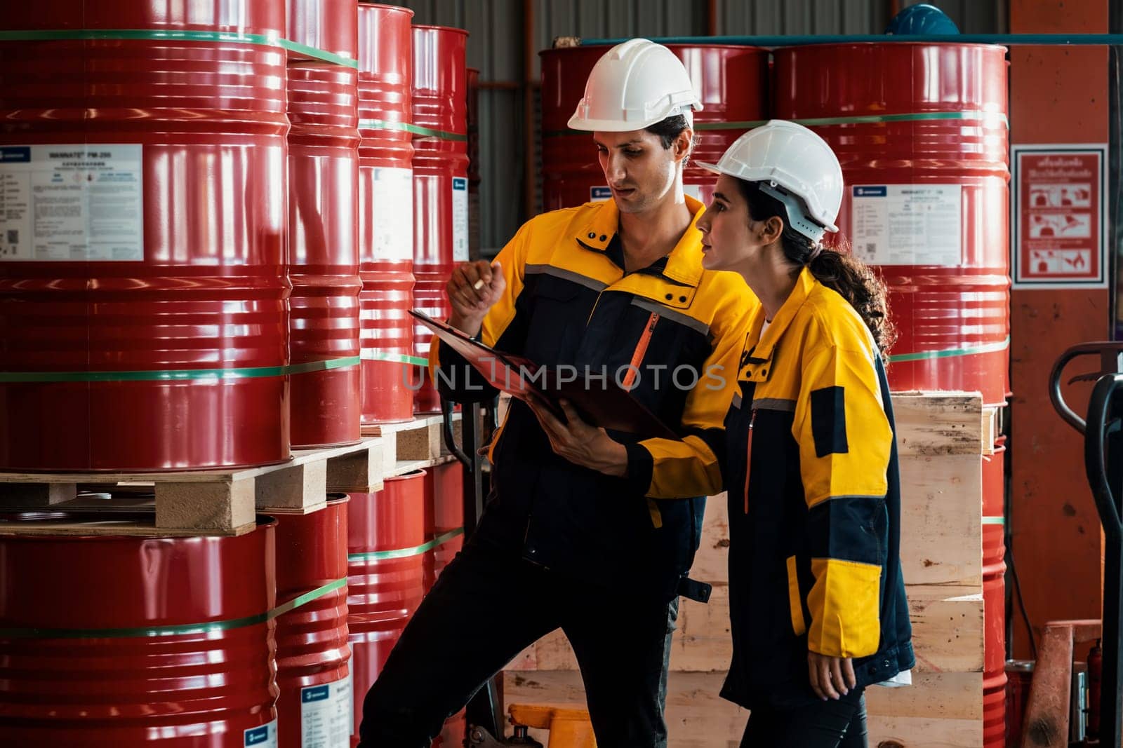 Two factory workers or inventory inspector conduct professional inspection on hazardous chemical barrels in warehouse, chemistry storage workplace and industrial profession concept. Exemplifying