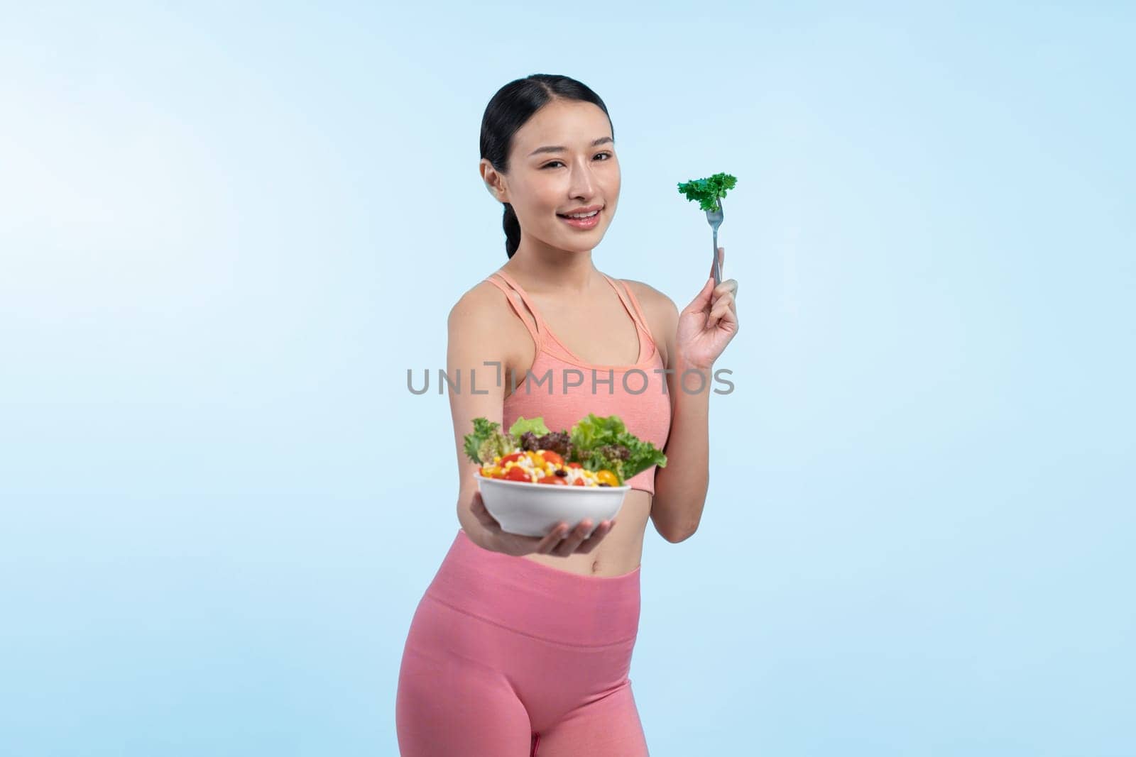 Asian woman in sportswear holding salad bowl on isolated background. Vigorous by biancoblue