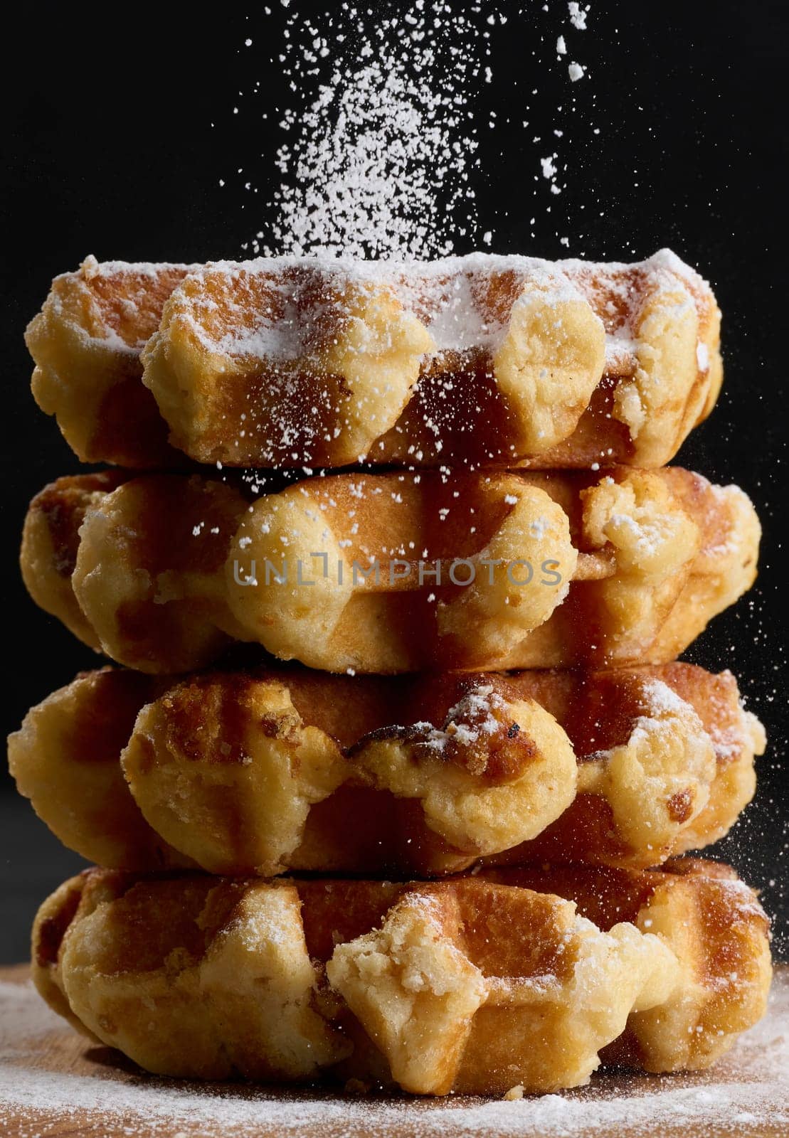 A stack of baked Belgian waffles sprinkled with powdered sugar by ndanko