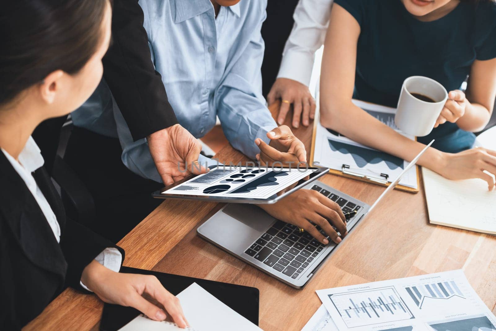 Multiracial analyst team use BI Fintech software to analyze financial data on meeting table. Financial dashboard data display on laptop screen with analyzed chart for marketing indication. Concord