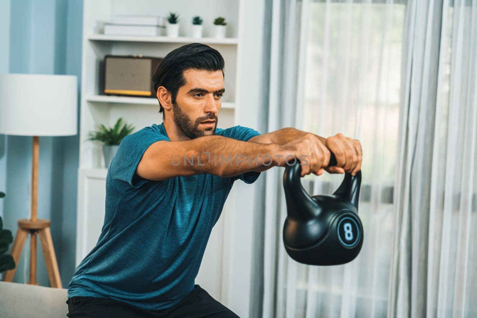 Athletic body and active sporty man doing squat with kettlebell weight for effective targeting muscle gain at gaiety home as concept of healthy fit body home workout lifestyle.