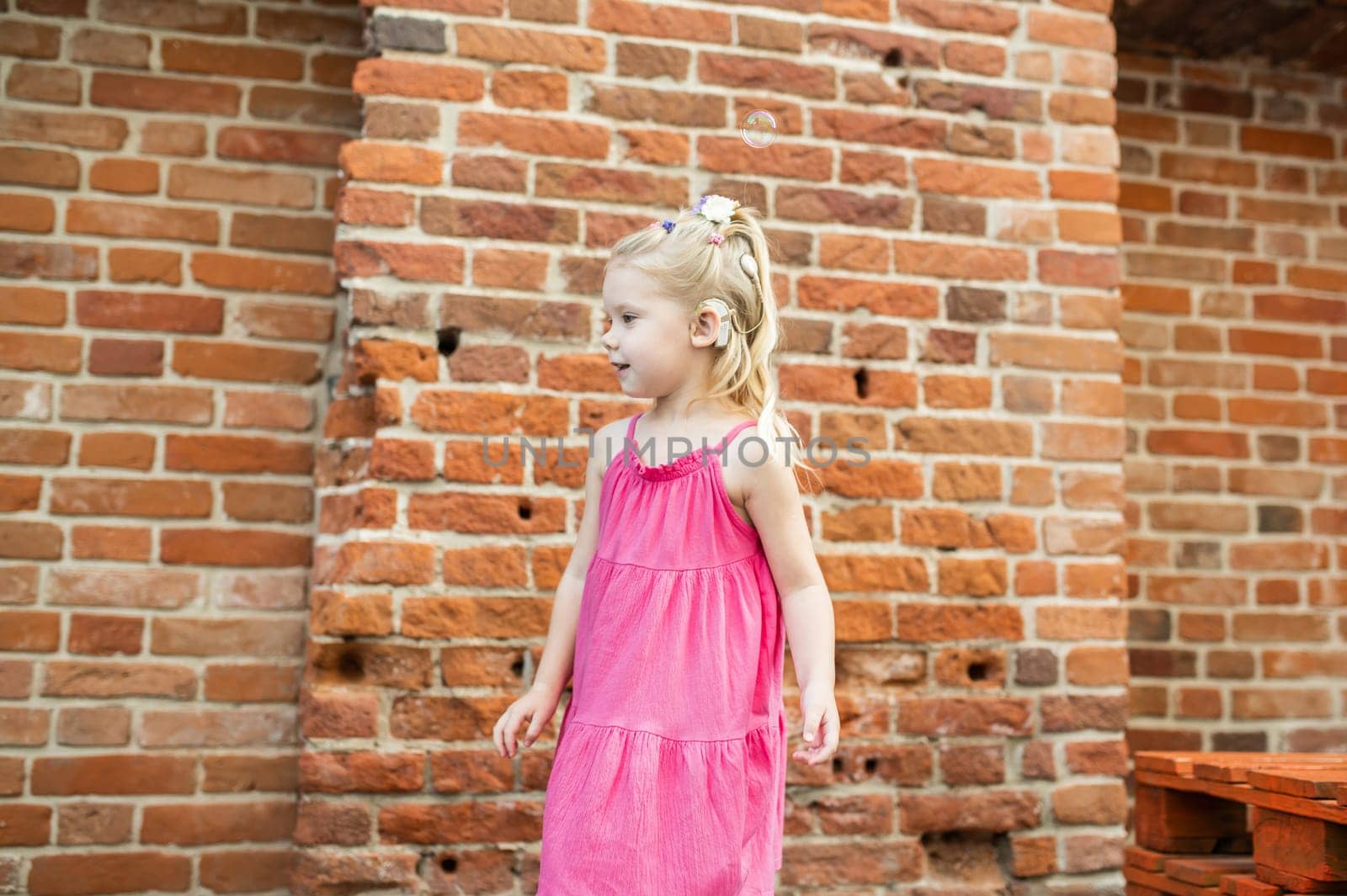 Child with hearing problem and cochlear implant dance in street, deaf kid began to hear. Hearing loss in childhood and treatment concept. Copy space and empty place for text.