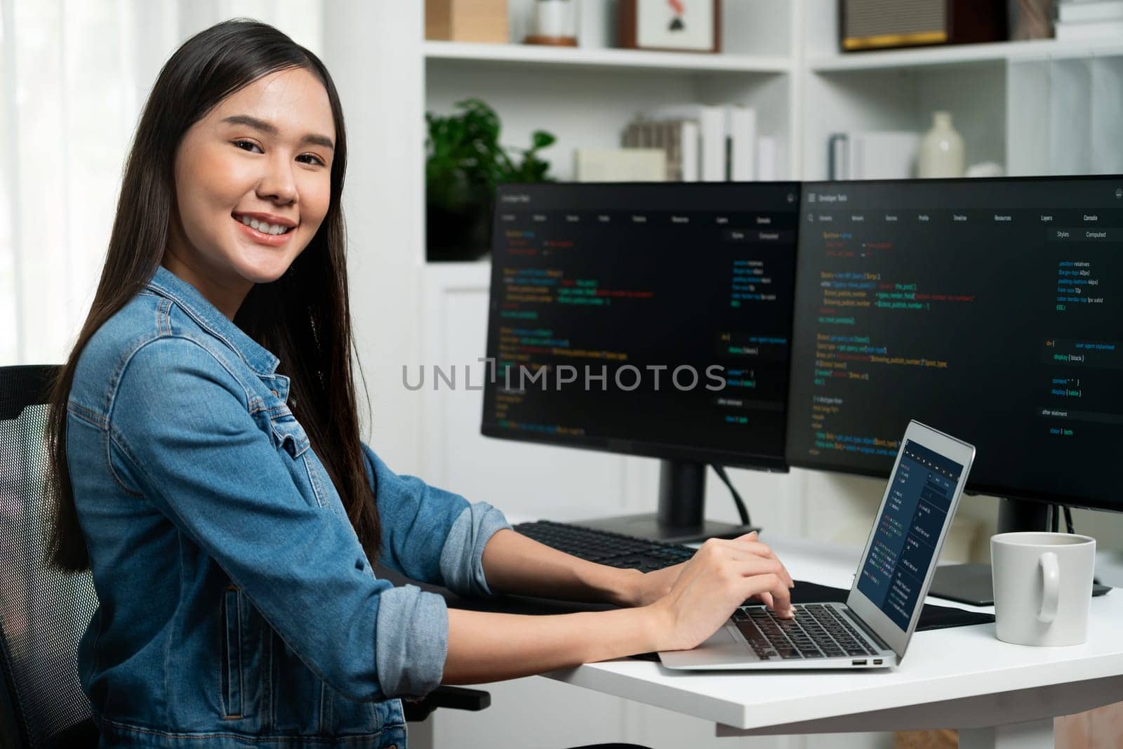 Young Asian in IT developer looking at camera to present with online information on pc with coding program data application, wearing jeans shirt. surround by safety analysis two screens. Stratagem.